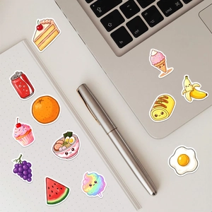 Close-up of cute cartoon food stickers with smiling faces on a laptop and notebook
