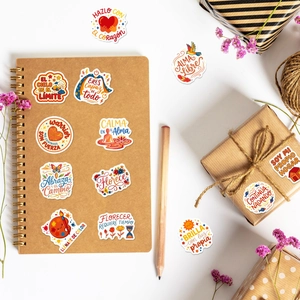 Detailed close-up of decorative Spanish motivational stickers on a kraft gift box