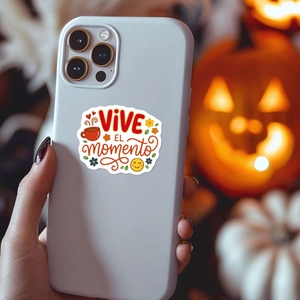 White phone case with Vive El Momento Spanish sticker against a festive pumpkin backdrop