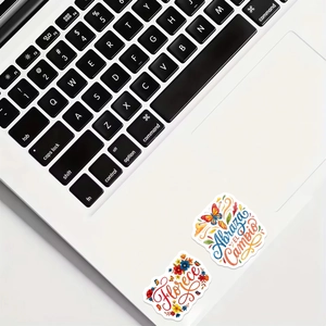 Close-up of Spanish inspirational stickers on a laptop with floral art designs