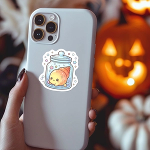 Close-up of a cute cartoon snail sticker on a grey phone case with warm festive decor