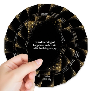 Close-up of black affirmation cards with gold glitter edges held in hand and fanned out