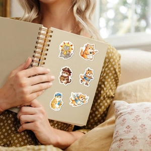 Gros plan d'autocollants de chats mignons sur un carnet tenu dans un cadre chaleureux