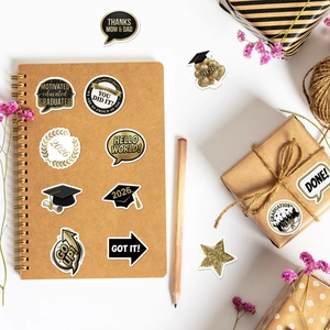 Detail of waterproof graduation stickers in black and gold on a notebook and gift box