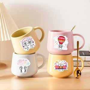 Mugs en céramique avec autocollants mignons et cuillère dorée dans un cadre chaleureux