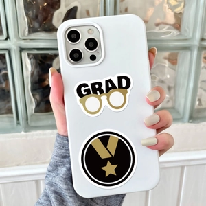 Close-up of graduate-themed stickers with GRAD letters and medal on a white iPhone case