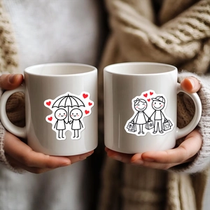 Close-up of ceramic mugs featuring romantic stick figure couples with a heart detail