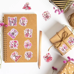 Flat lay of pink Valentine skull stickers on a kraft notebook with decorative props