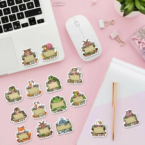 Flat lay of cute animal stickers with blank wooden signs on a laptop and pink desk