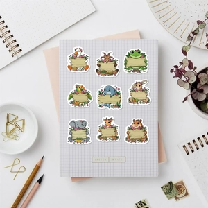 Close-up of nine cute cartoon animal stickers with blank wood signs on a grid notebook