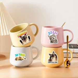 Set of four colorful ceramic cat mugs with funny expressions and golden spoons