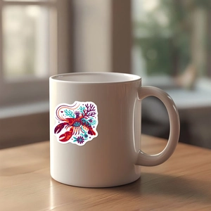 Artistic colorful lobster illustration printed on a glossy white ceramic mug on a wooden table