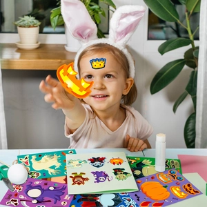 Bambina che gioca con adesivi colorati di Halloween con zucche e fantasmi divertenti
