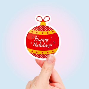 Handheld view of a round red Happy Holidays sticker with yellow accents and a bow detail