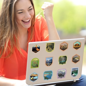 Detail of vintage US National Park stickers on a laptop used outdoors by a woman