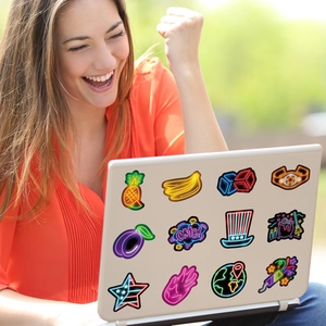 Creative neon stickers on a laptop lid with colorful fruits and funny symbols