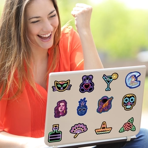 Vibrant neon vinyl stickers decorating a laptop featuring astronaut and summer party designs