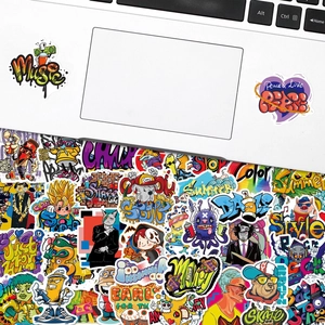 Close-up of vibrant graffiti stickers applied to a white laptop and scattered on surface
