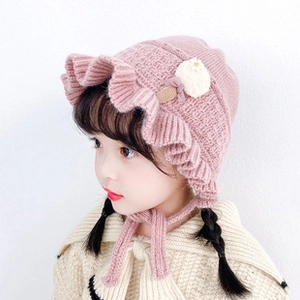 Detailed close-up of pink knit hat with floral and ice cream accents and ear flaps