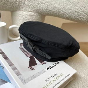 Detail of black beret with buckle strap on a white book in a cozy setting