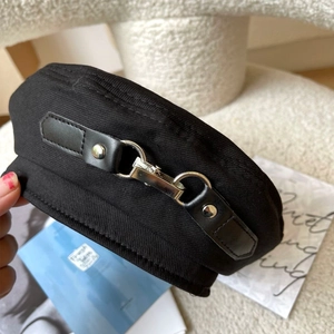 Close-up of black cotton beret featuring leather strap and silver metal buckle detail