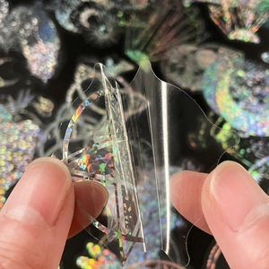 Macro shot showing holographic PET sticker transparency and peeling adhesive layer