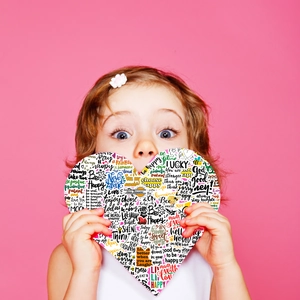 Gros plan d'un enfant tenant un autocollant en forme de cœur avec des citations