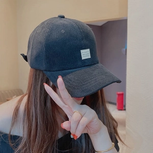 Close-up of charcoal gray corduroy beanie showing striped texture and square logo patch