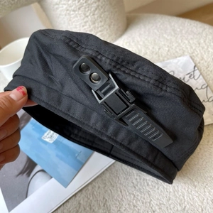 Detail of black beret featuring a canvas texture with buckle strap and tactical side detail