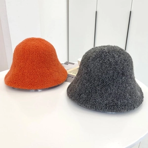 Dettaglio dei cappelli a secchiello arancioni e grigi in lana d'agnello riccia