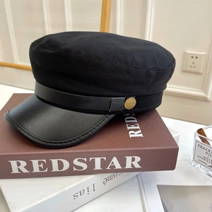 Detailansicht der Kapitänsmütze mit Lederschirm und goldener Vintage-Taste auf Büchern