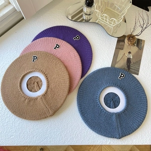 Detailed knit texture of four beret hats in pastel colors with embroidered P patch