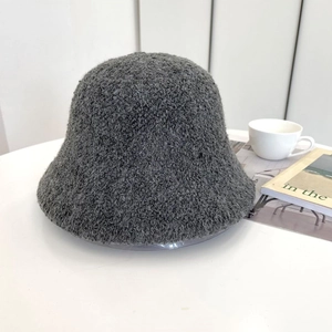 Dettaglio cappello a secchiello in maglia bouclé grigio scuro su scrivania bianca