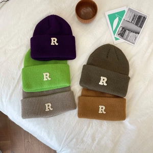 Detailweergave van kleurrijke geribbelde gebreide mutsen met witte letter R-patch erop