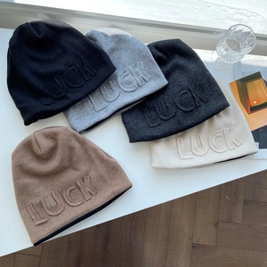 Close-up of knit beanies in five neutral colors featuring Luck embossed lettering details