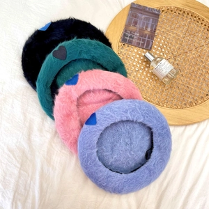 Flat lay of colorful plush rabbit fur beret hats with minimalist heart embroidery