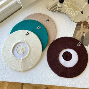 Flat lay of knit beret hats in white, green, khaki, and brown with letter P patch