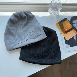 Close-up of LUCK letter patch on grey and black knitted beanies with soft texture