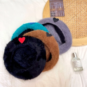 Detail of four fluffy rabbit fur berets in multiple colors with heart embroidery patches