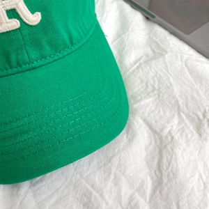Detail of green baseball cap featuring white 3D letter embroidery and double stitching