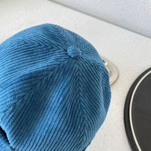 Detailed close-up of dark blue corduroy cap crown with fabric button and texture