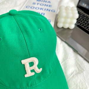 Close-up of bright green cotton baseball cap featuring detailed white R letter embroidery