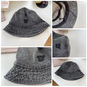 Dettaglio del cappello alla pescatora in denim grigio con ricamo nero della lettera D