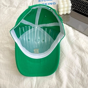 Detail view of the interior structure and white sweatband of a green cotton baseball cap