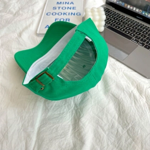 Close-up of adjustable metal buckle strap on a green cotton baseball cap with cotton texture