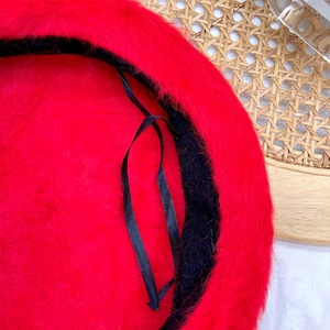 Detail of red plush beret showing fluffy texture and inner adjustable strap system