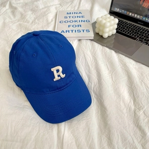 Detail of blue cotton baseball cap with white R embroidery on a lifestyle background
