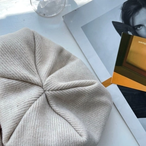 Macro detail of fine stitching on top of beige knit beanie showing premium wool texture