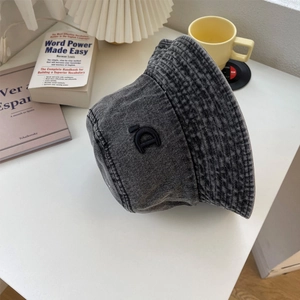 Dettaglio del cappello pescatore in denim lavato vintage con ricamo di lettera nera su cotone