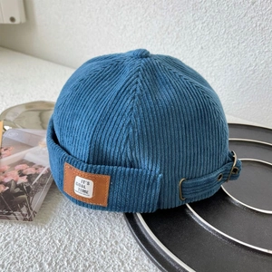 Detail of navy corduroy skull cap with a leather patch and adjustable metal buckle